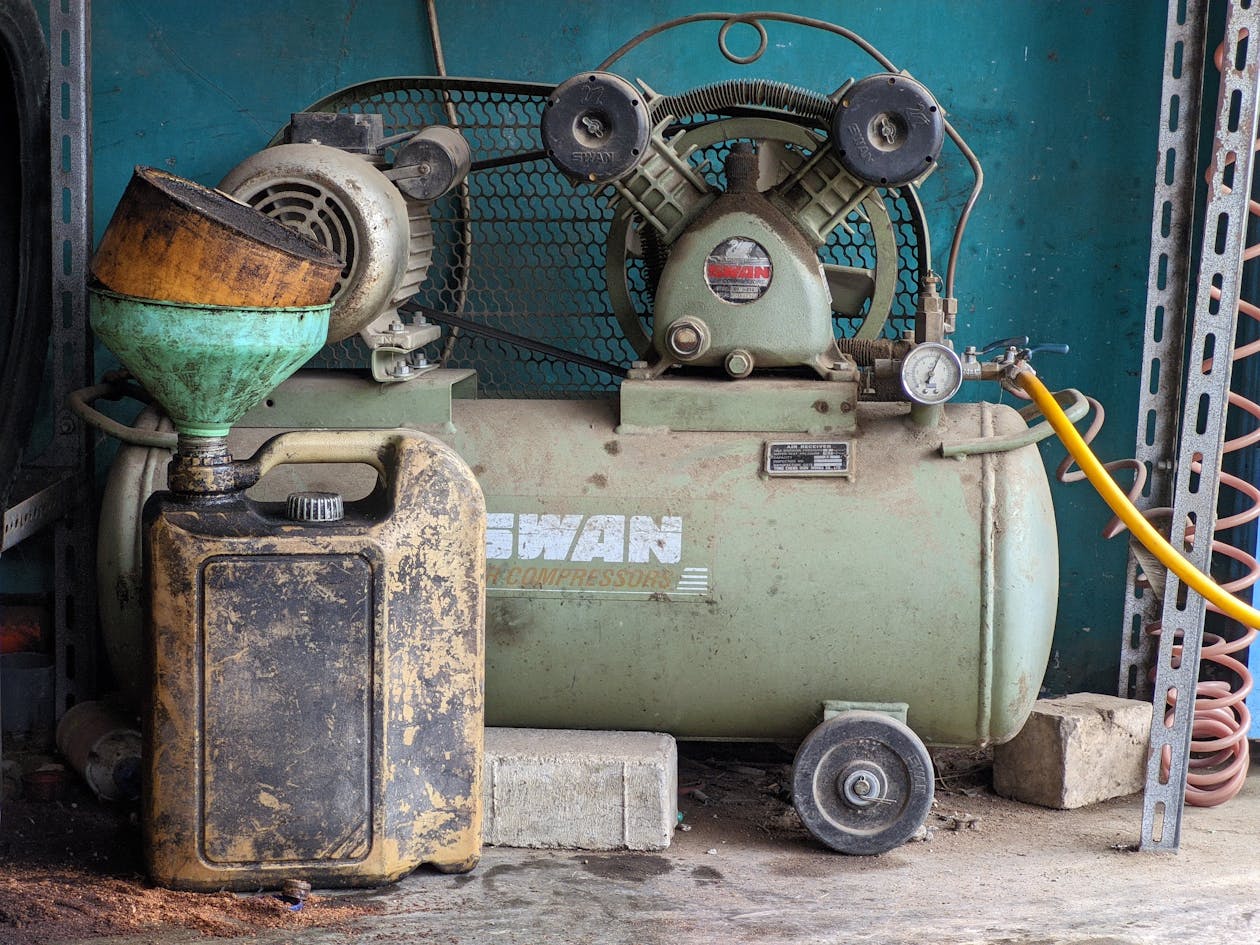Vintage air compressor in a workshop with oil can