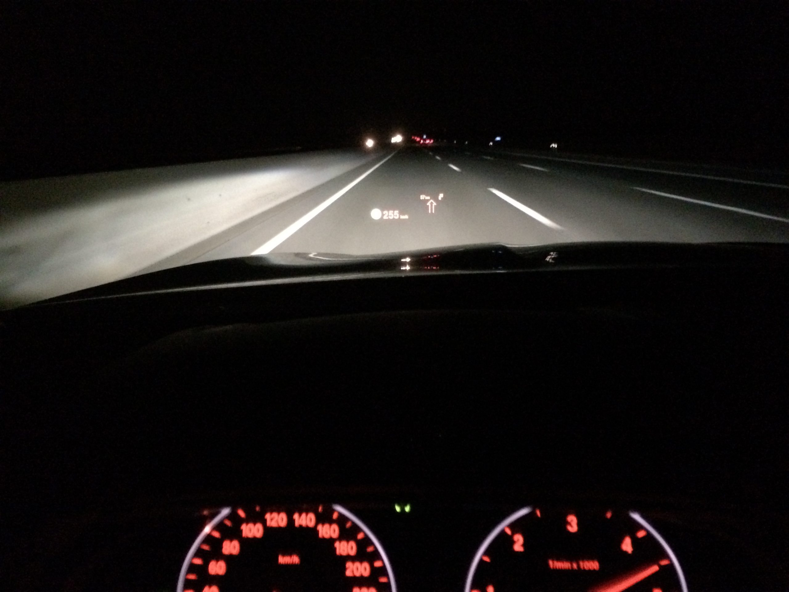 Head up display projected onto the windshield of a BMW F11 at night showing speed and navigation information