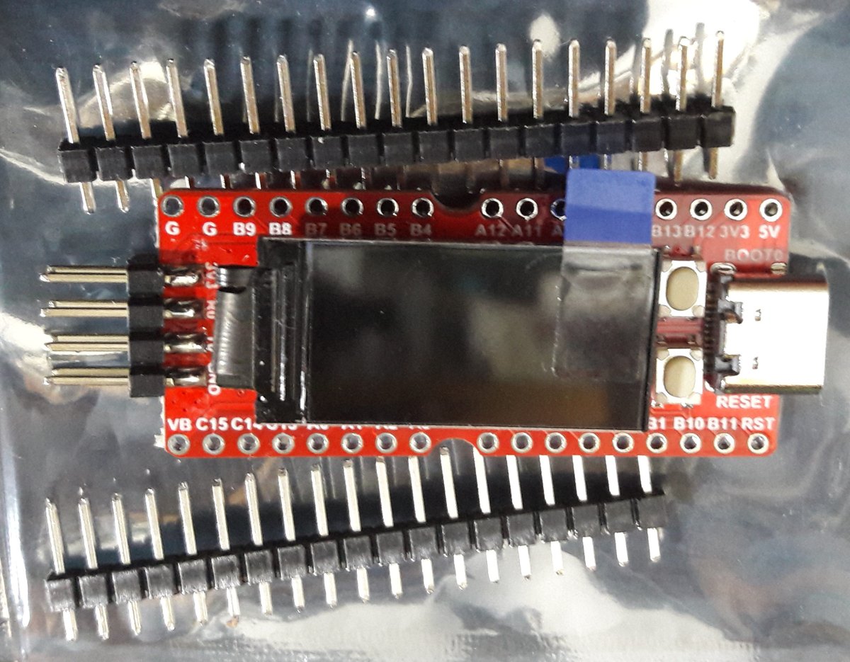 A red Sipeed Longan Nano development board with a small colour LCD and labelled header pins
