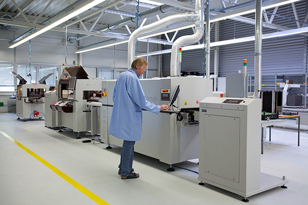 A surface-mount assembly line in an electronics factory, with a worker at a control station
