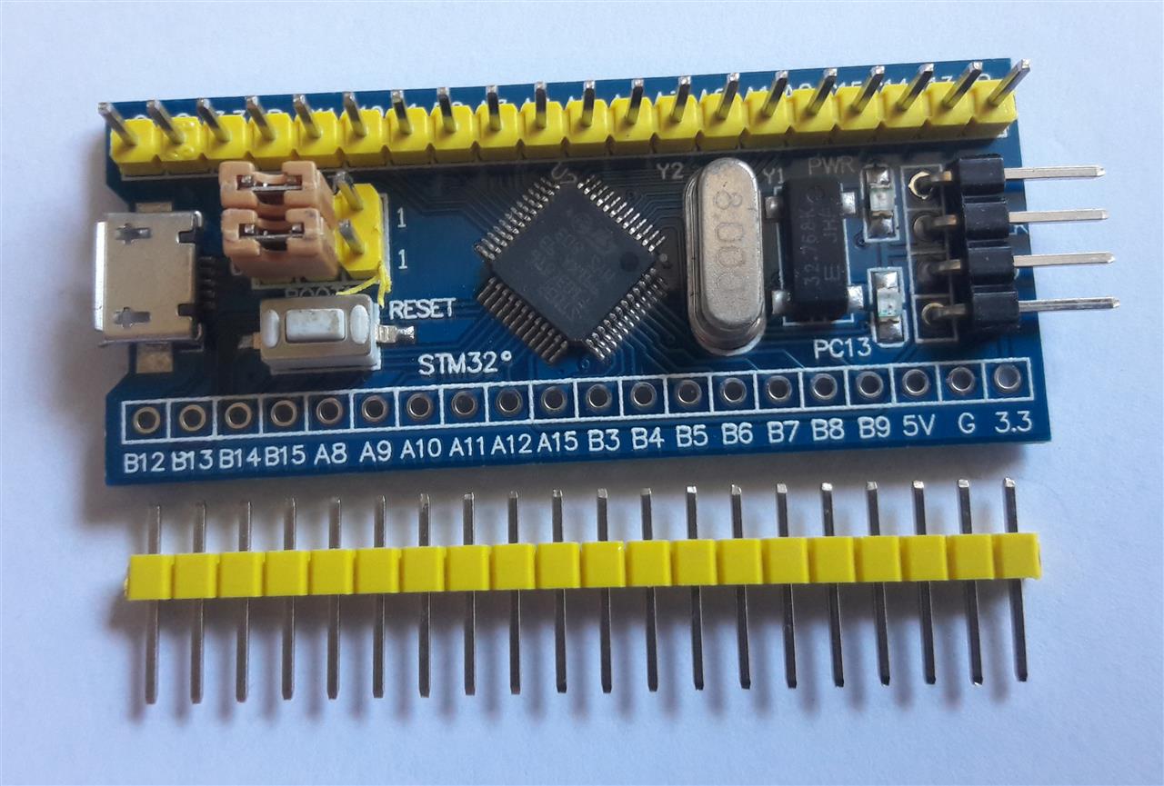 A blue STM32F103 development board with the STMicroelectronics Cortex-M3 microcontroller in an LQFP package at its center, an 8 MHz crystal and labeled GPIO headers around it.