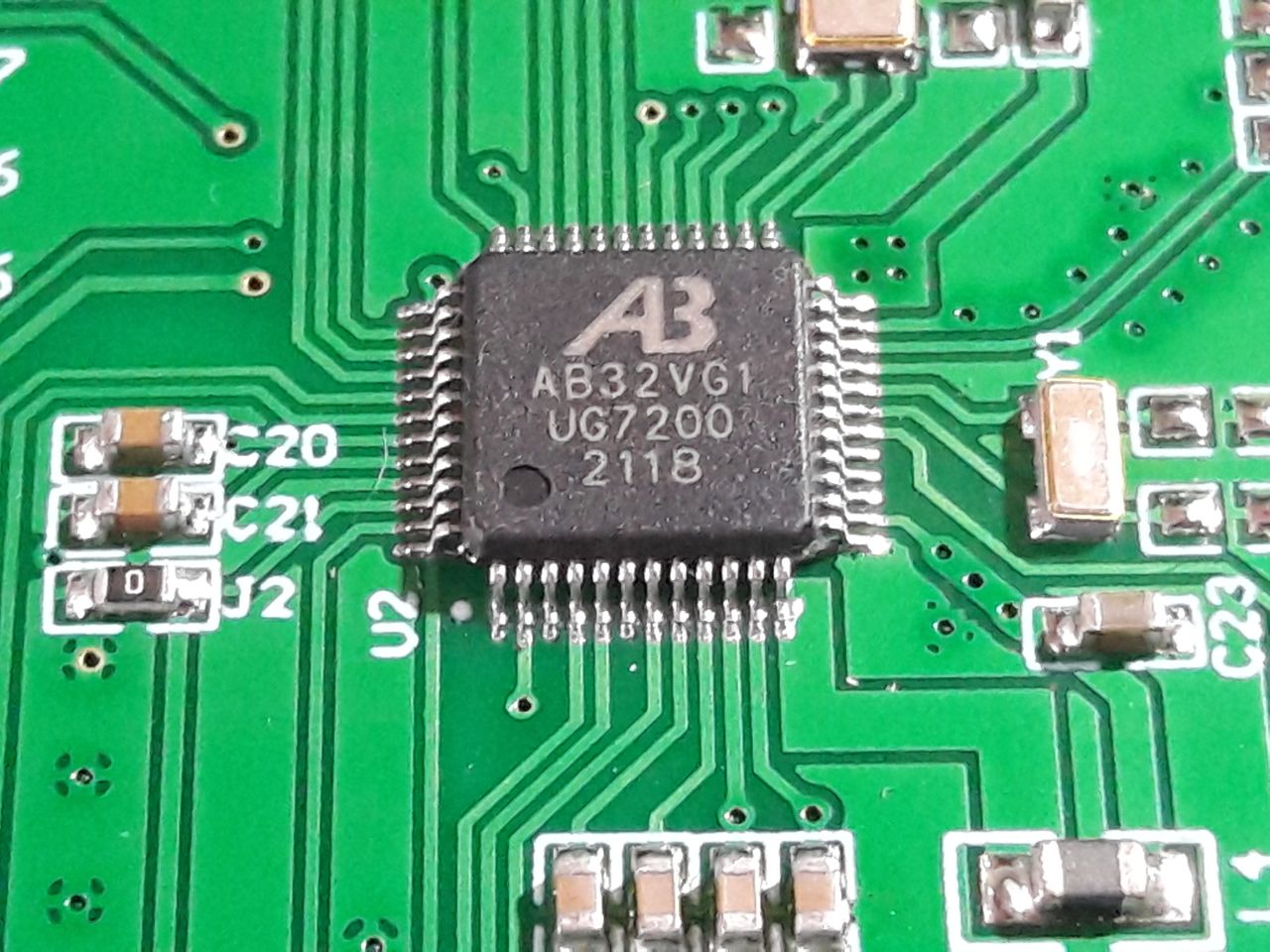 A Bluetrum AB32VG1 RISC-V system-on-chip in an LQFP package soldered on a green circuit board, surrounded by passives and a crystal, with the part marking AB32VG1 UG7200 visible.