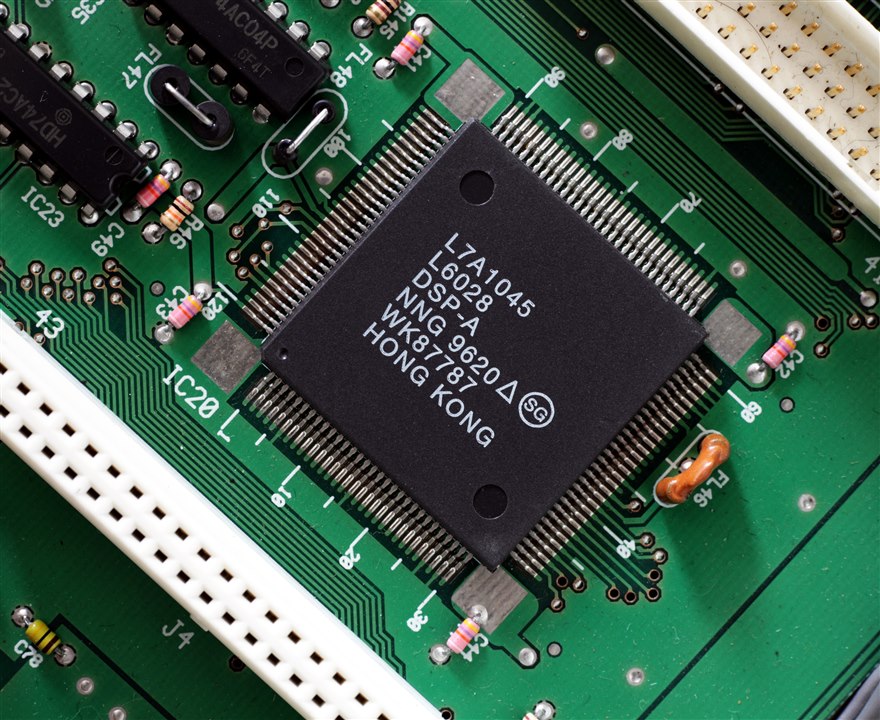 A standalone DSP in a QFP package marked DSP-A soldered onto a circuit board, surrounded by logic ICs and passive components.