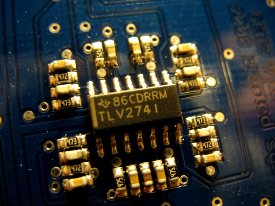 A TI TLV2741 surface-mount operational amplifier soldered on a blue PCB, surrounded by SMD resistors and capacitors.
