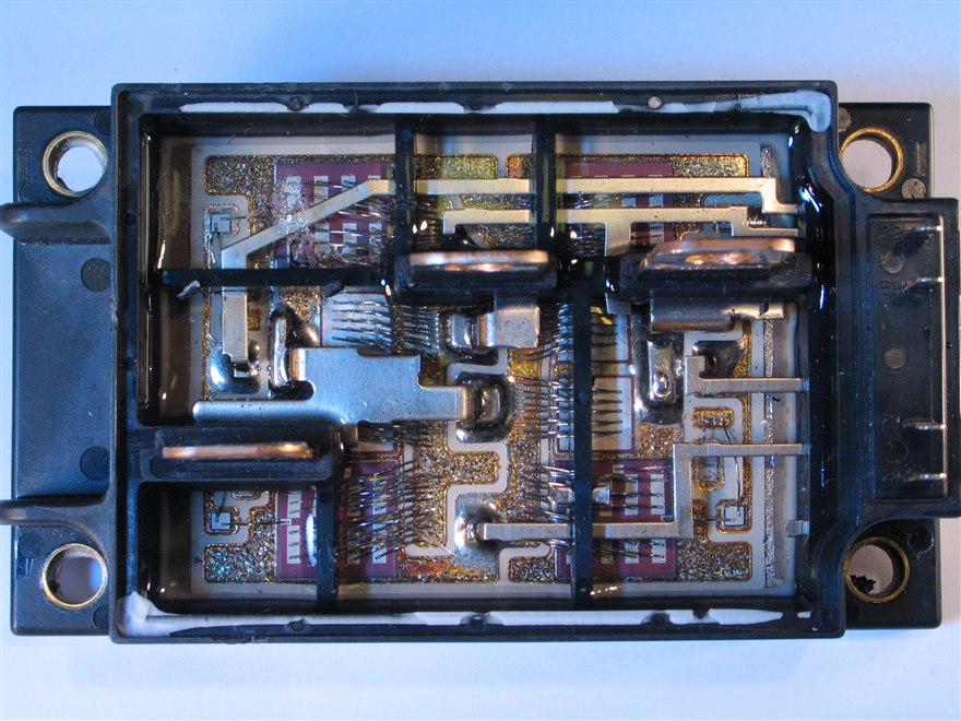 The inside of an IGBT power module with its lid removed, the dies, bond wires and copper traces visible.