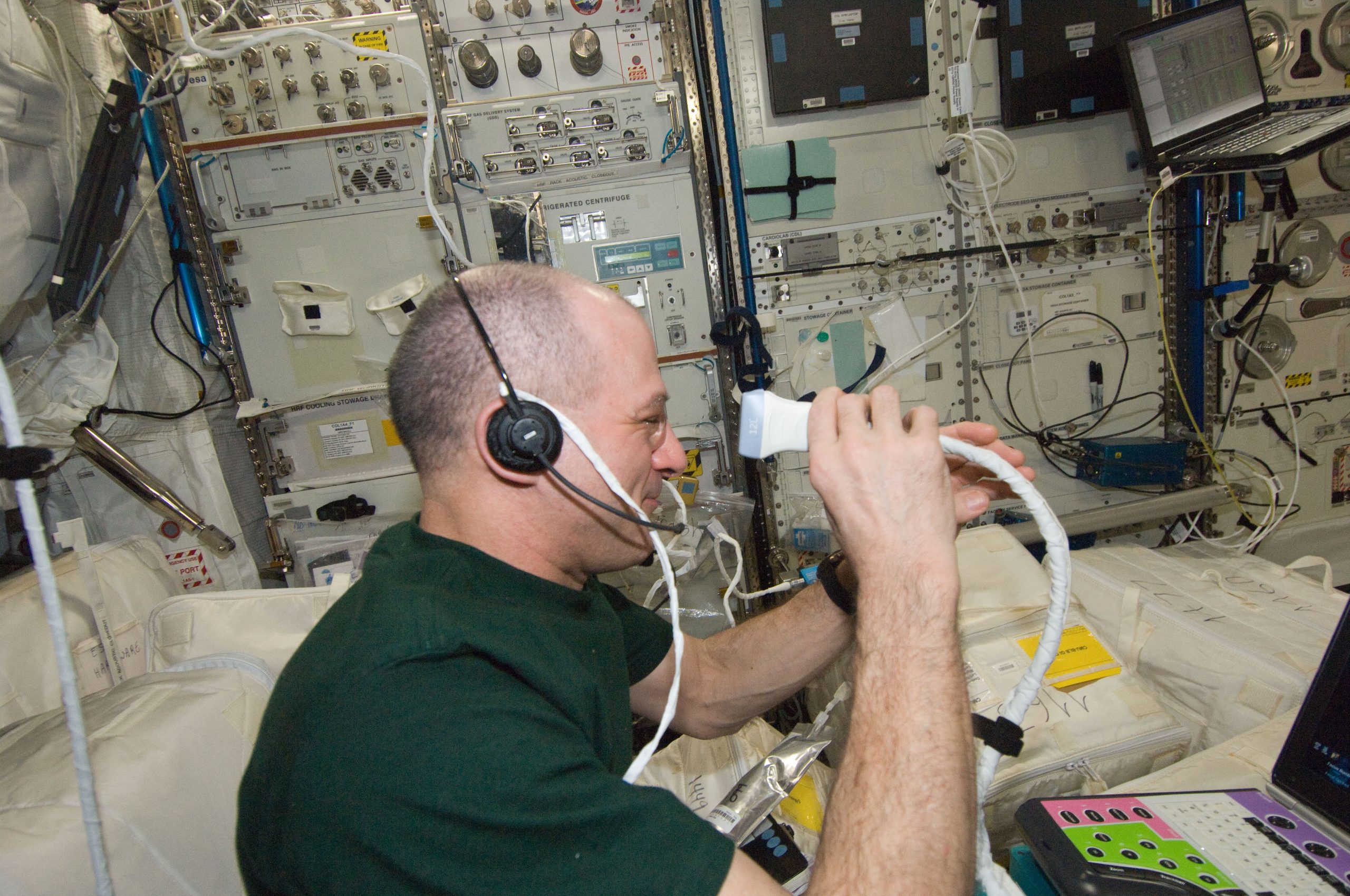A person holding a small handheld ultrasound probe to a closed eye, the scan run one-handed.