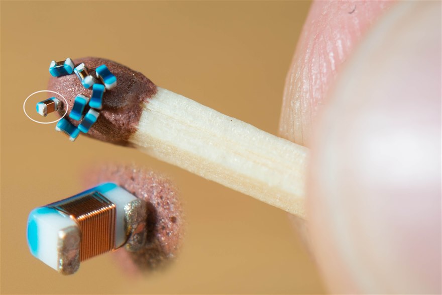 Surface-mount chip inductors beside a match head for scale, including a wirewound power inductor showing its copper coil.