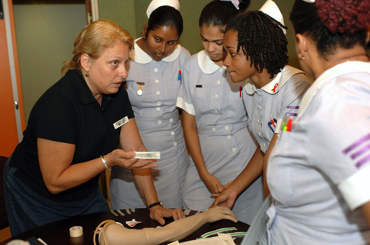 A nurse teaching student nurses the steps of starting an intravenous line on a practice arm