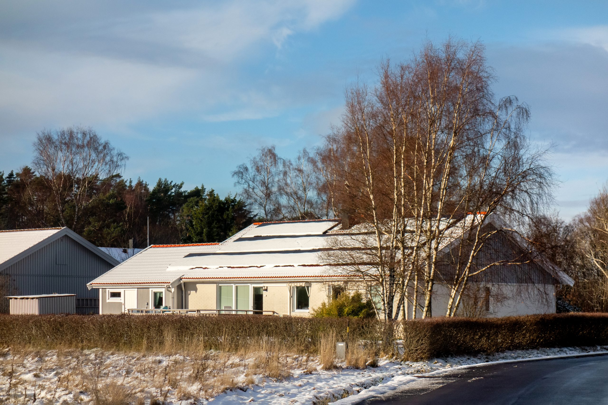 Solar panels covered in snow on the roof of a house in a winter landscape