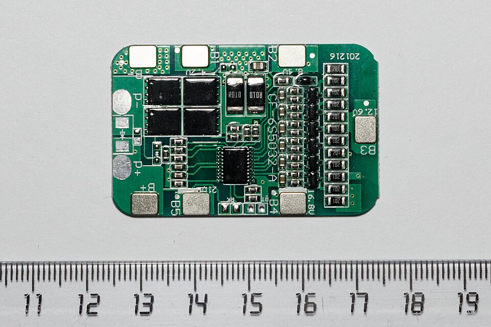 A generic six-cell battery management board on a centimetre ruler for scale