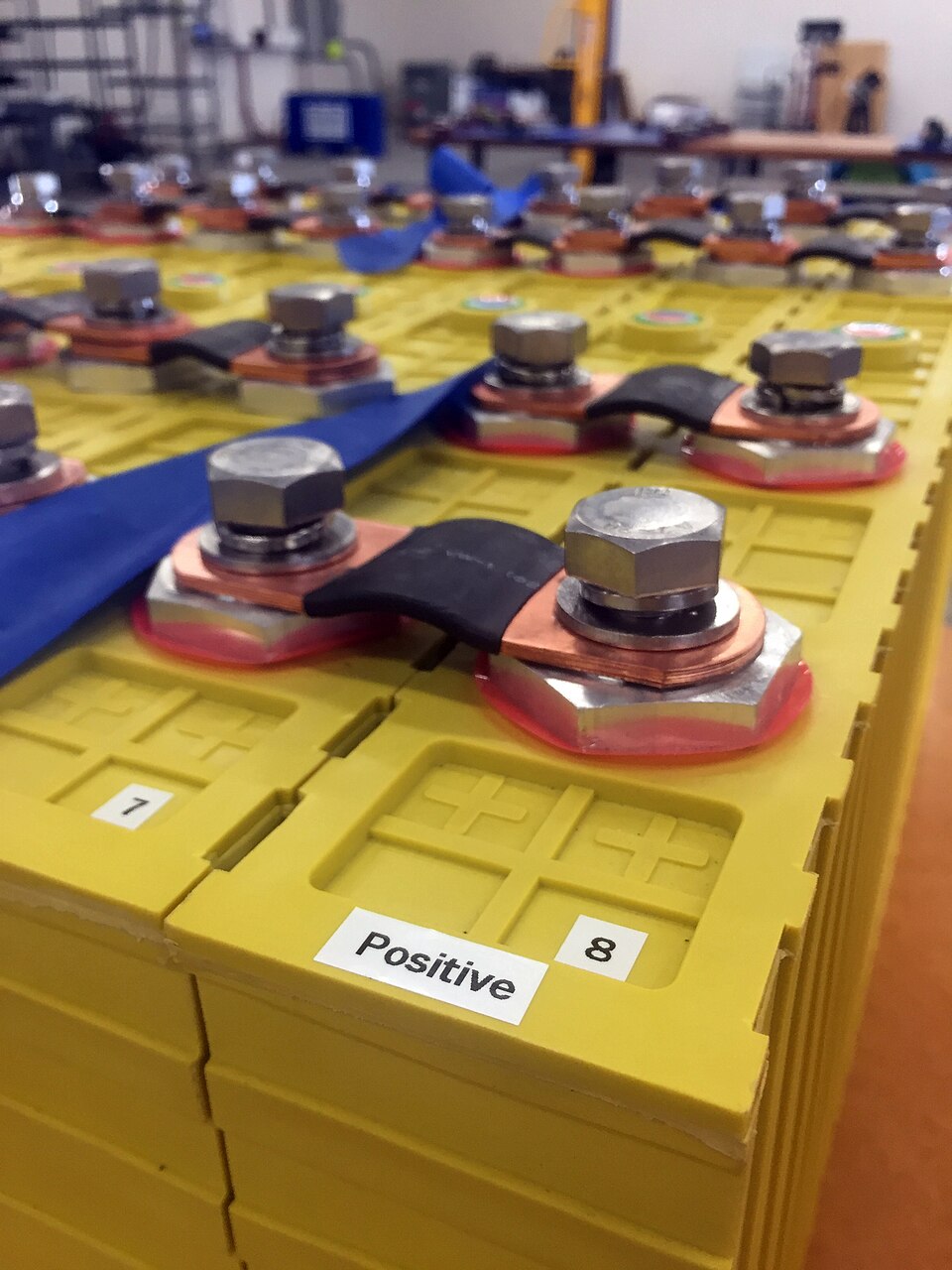 Large prismatic LiFePO4 cells joined by bolted copper busbars across their terminal posts