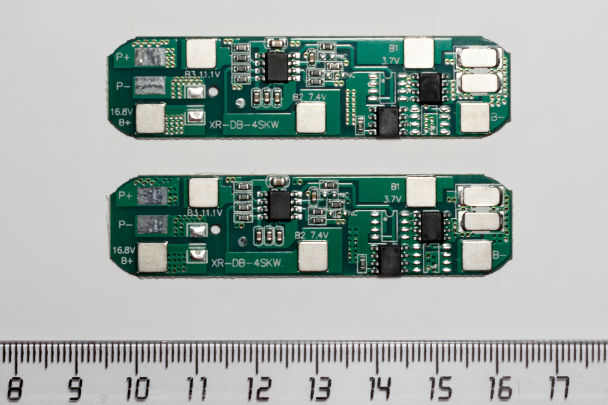Two generic 4S LiFePO4 BMS protection boards photographed above a centimetre ruler