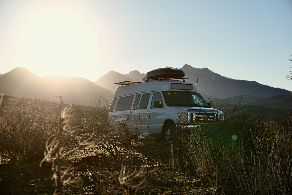 High-roof campervan parked in the mountains at sunset
