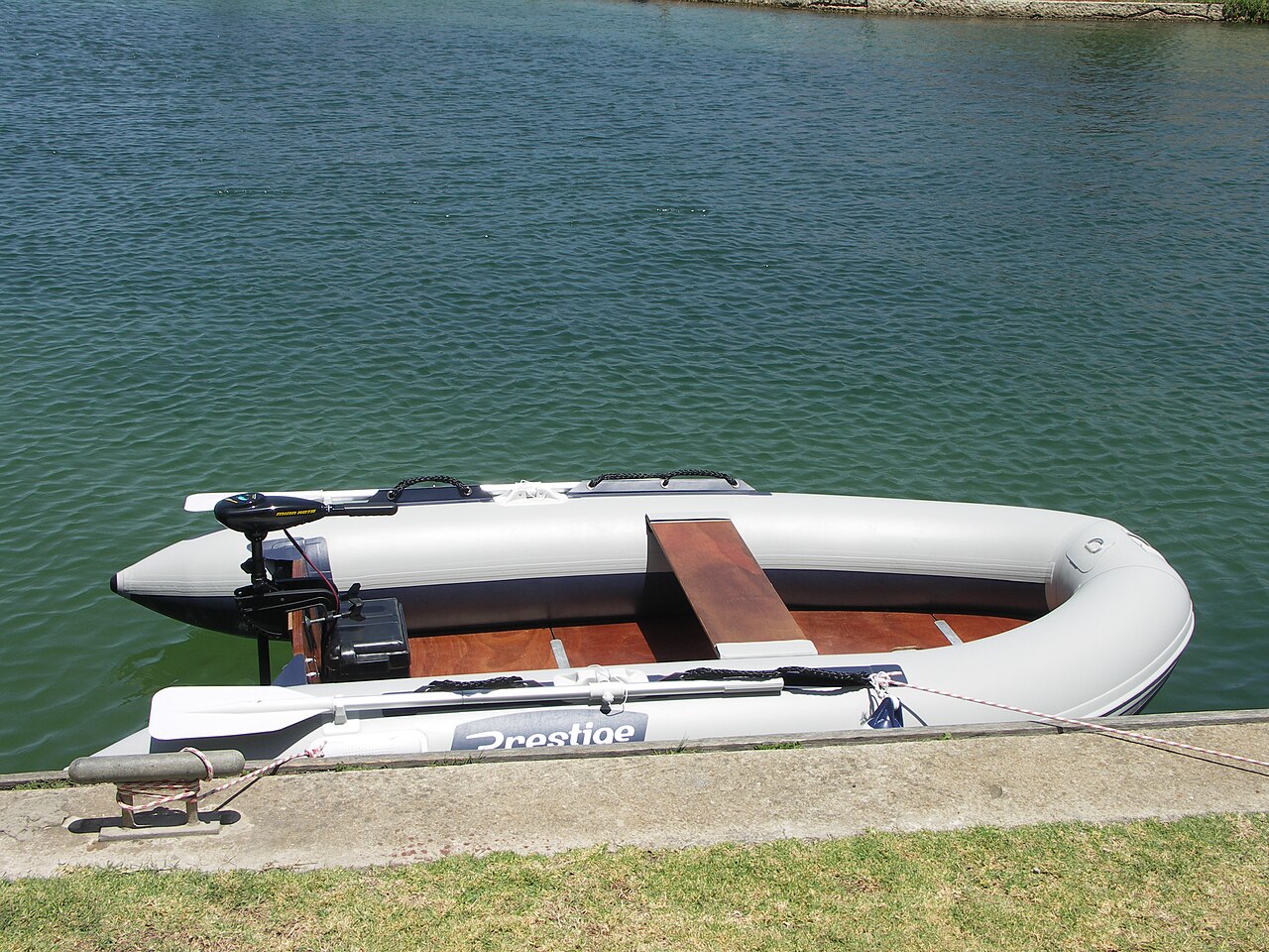 Inflatable boat at a dock with transom trolling motor and battery box