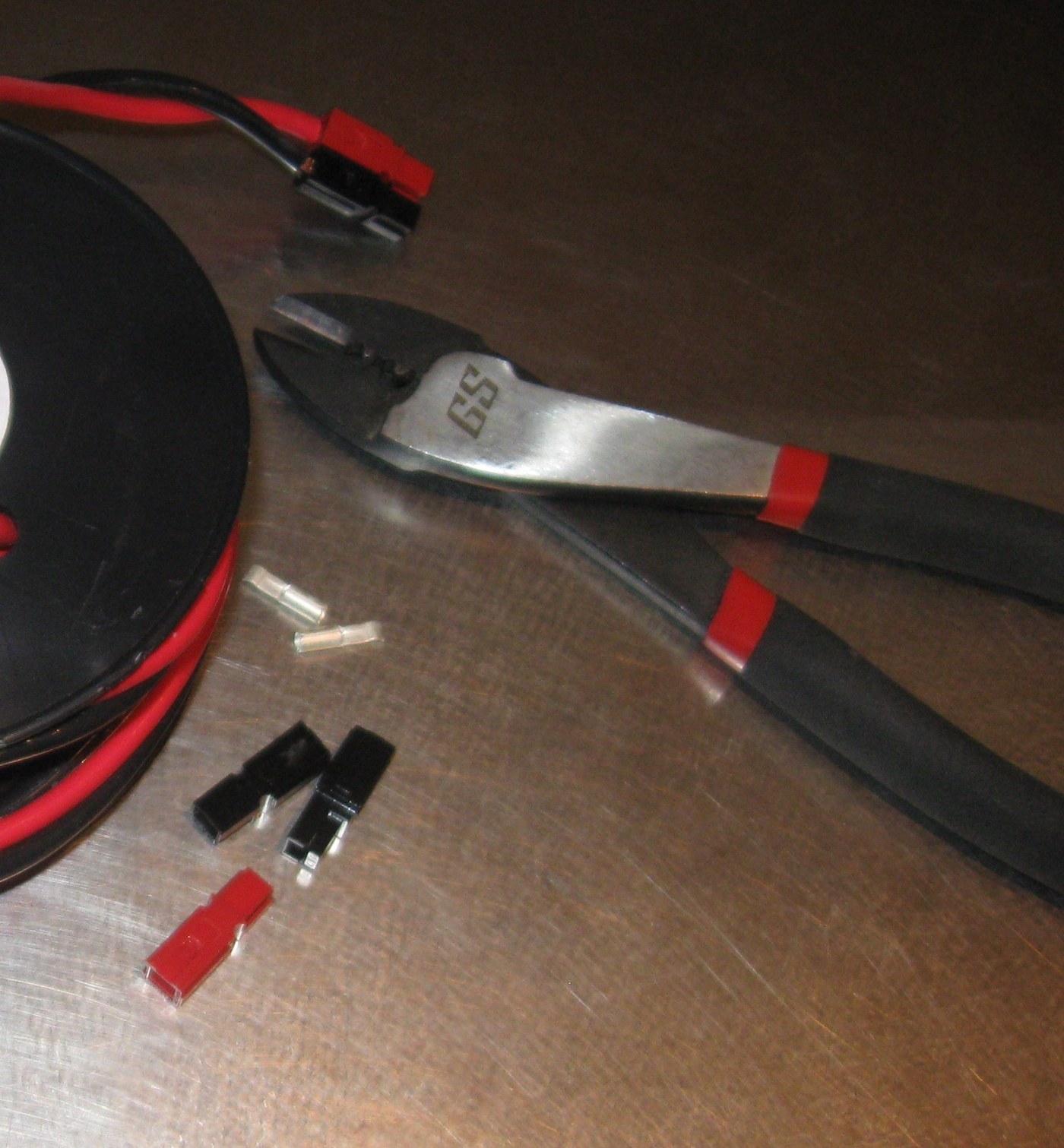 Anderson Powerpole housings, loose contacts and a crimping tool on a bench