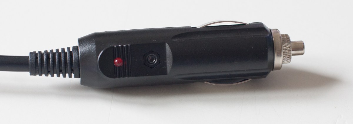 A black cigarette-lighter style 12 volt plug with sprung centre tip, knurled screw-off nose, side spring leaves and a red indicator lamp