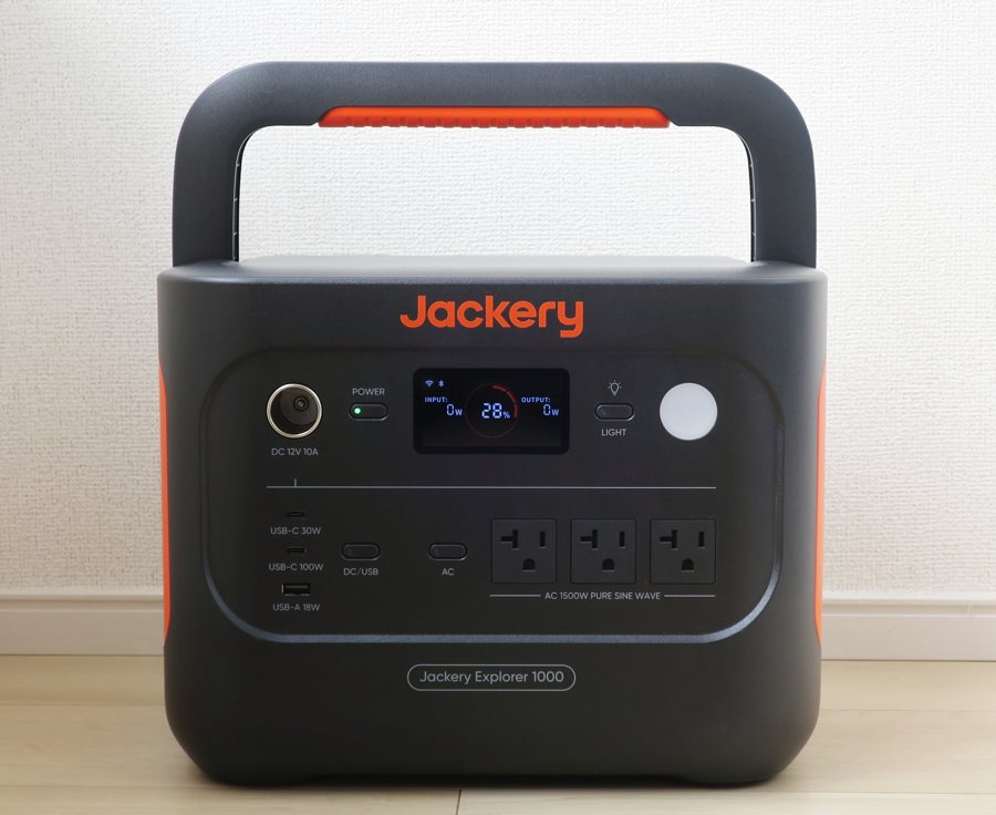 Front panel of a Jackery Explorer 1000 showing DC 12V 10A socket, USB-C 30W and 100W ports, USB-A 18W port, three AC sockets marked AC 1500W pure sine wave, and a display with input and output lines