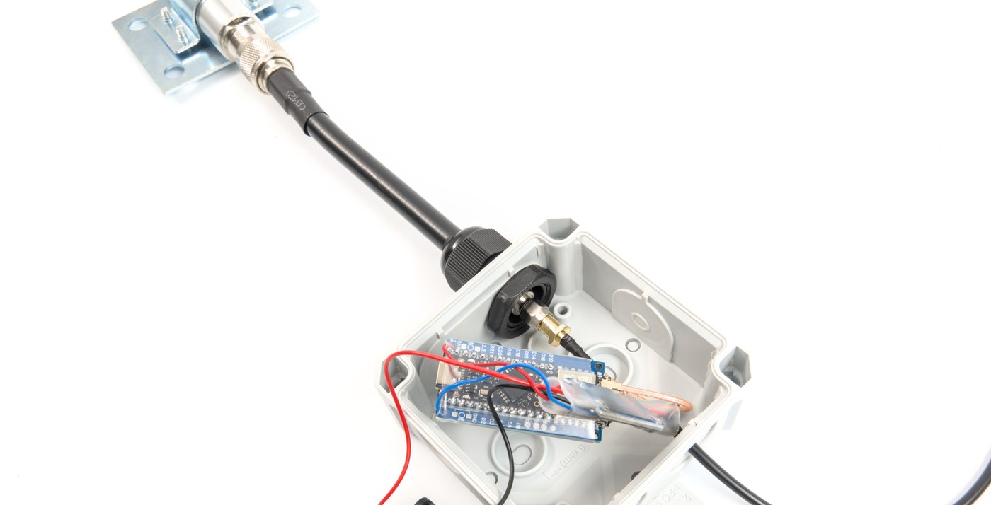 A sealed enclosure with its lid off, showing a threaded cable gland where a cable passes through the wall