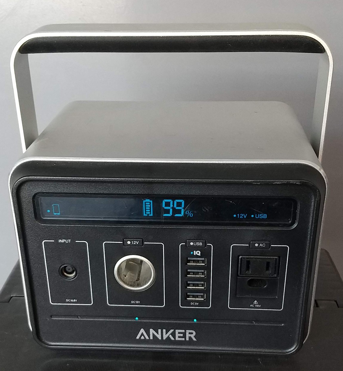 Front panel of a portable power station with its display reading 99 percent, showing the DC input, a 12 volt socket, four USB ports and one AC outlet