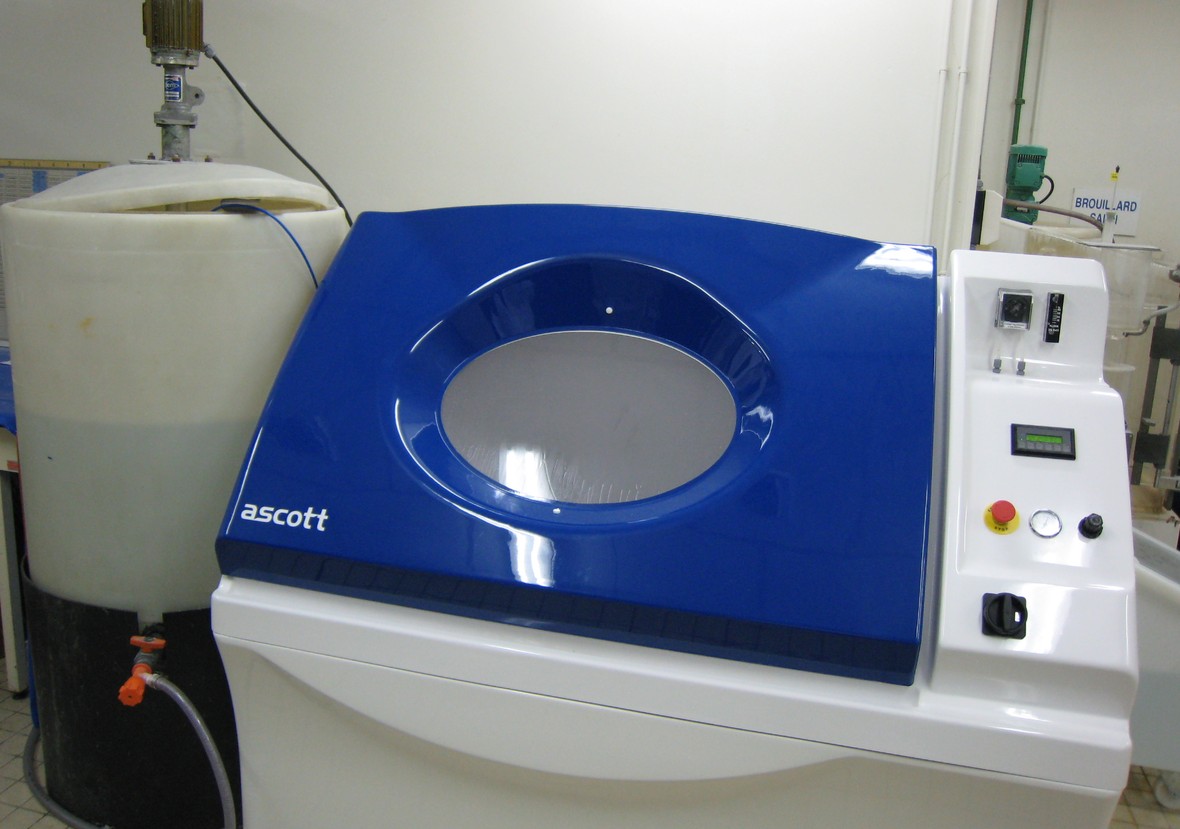 Blue and white salt spray test chamber in a laboratory with a brine reservoir tank beside it