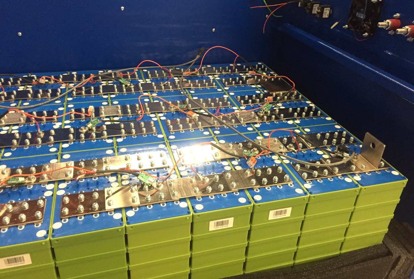 A bank of prismatic lithium iron phosphate cells joined by busbars, with balance leads running to each terminal