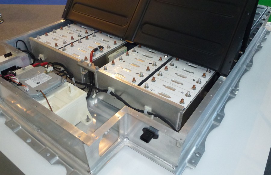 An opened battery pack showing prismatic cells bolted into modules inside an aluminium tray with a wiring harness