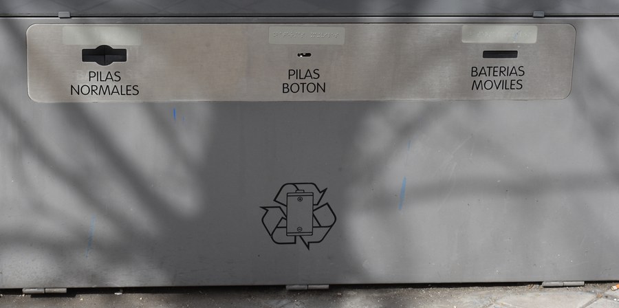 A public battery collection point with separate slots labelled for household cells, button cells and phone batteries