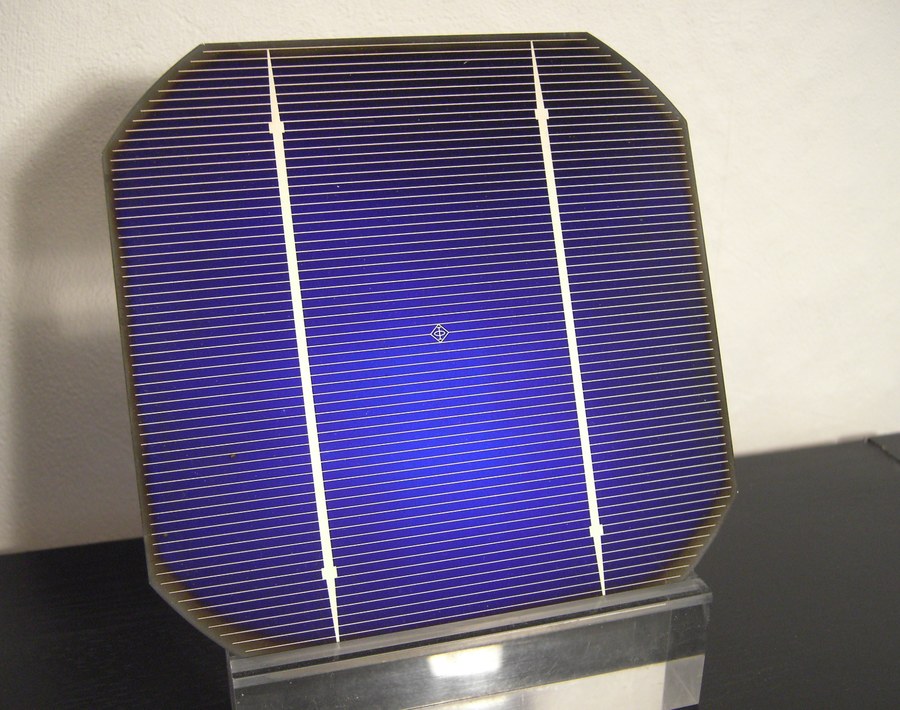 A finished 125 millimetre pseudo-square monocrystalline solar cell with chamfered corners, blue anti-reflective surface, fine silver fingers and two wider busbars
